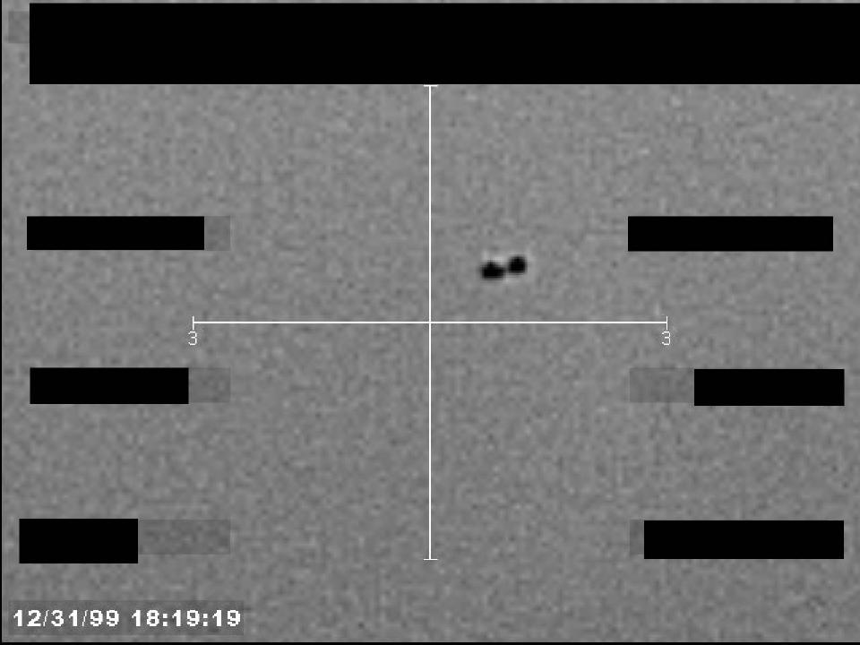 Redacted sensor image with a targeting reticle centered on an object.