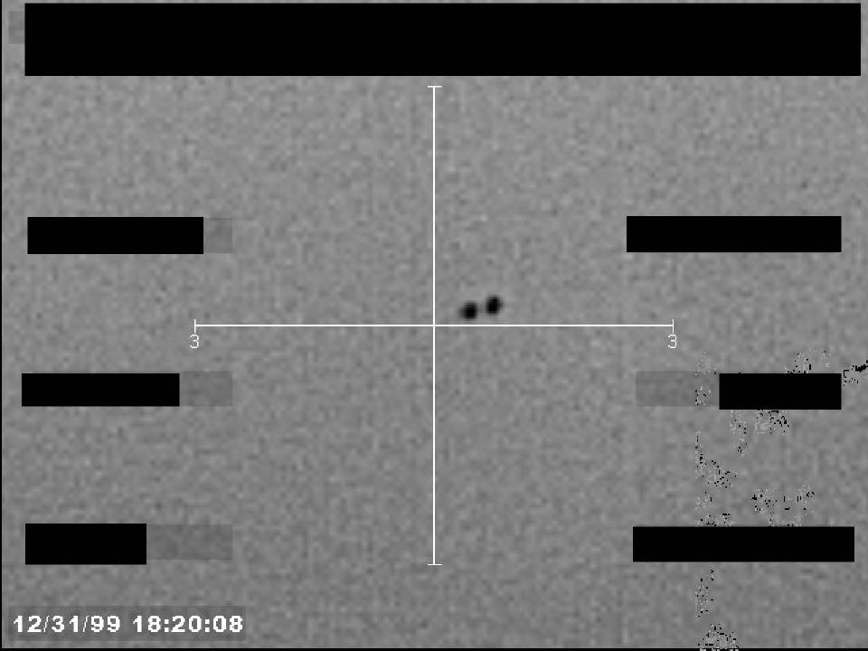 Redacted sensor image with a crosshair targeting a visible object.